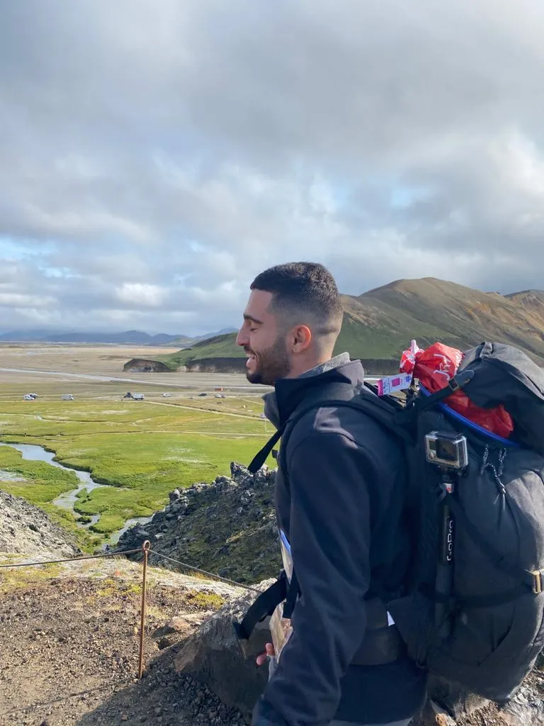 Nir smiling on a trail above a green valley in Iceland